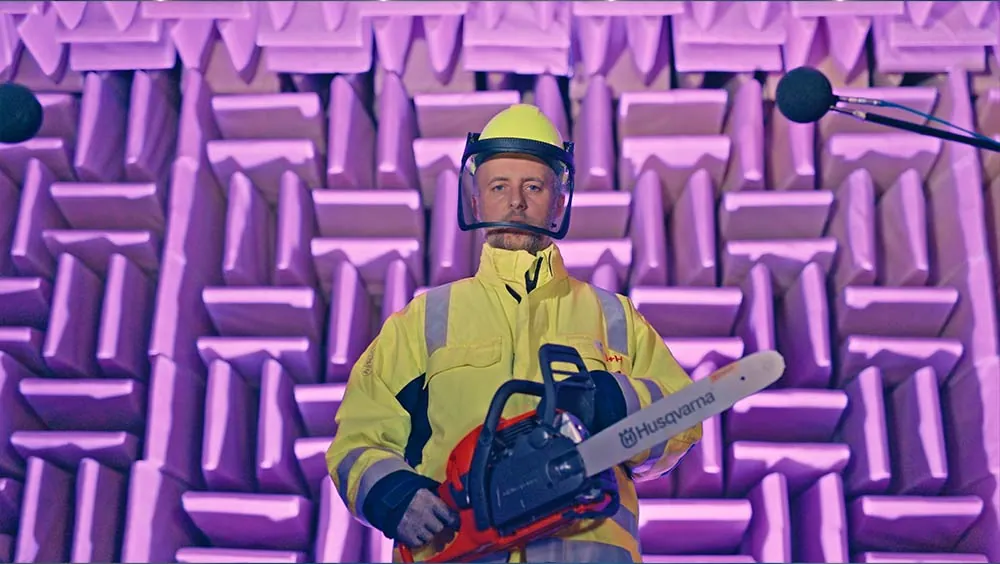 Arbeiter mit Kettensäge in Schutzkleidung in einem Raum für Schallvermessung